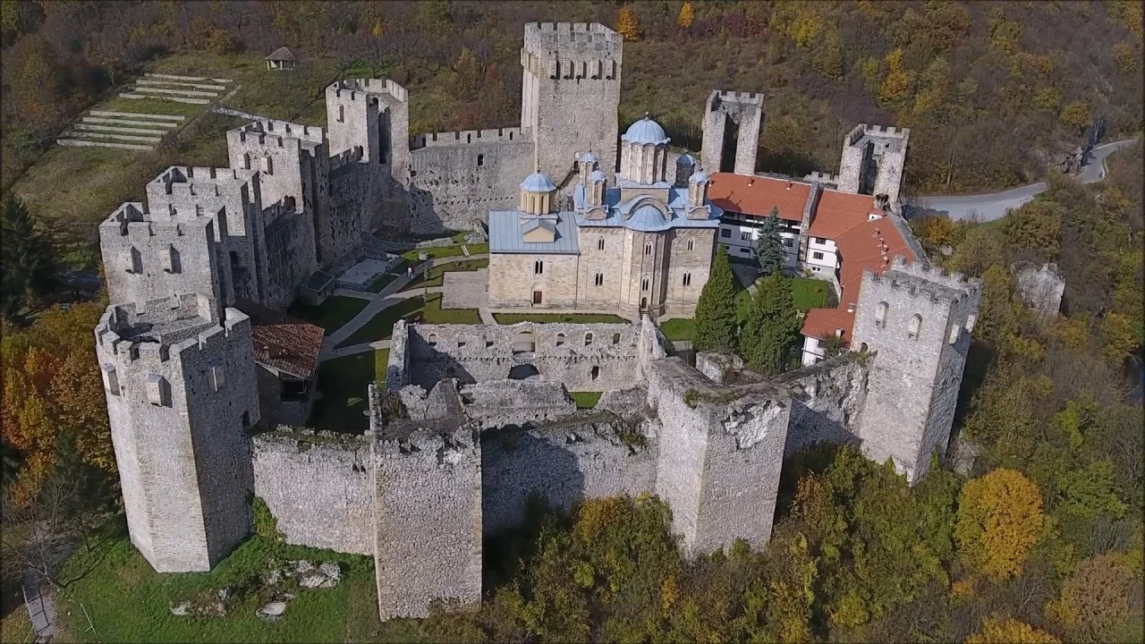Aerial view of the fortified Manasija monastery with stone towers among autumn trees